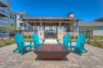 two blue adirondack chairs sit around a fire pit in the middle of a brick